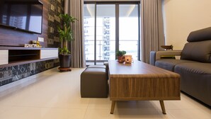 A modern living room with a flat-screen TV, a wooden coffee table, a sofa, and a large window with a city view. - JAgape (Johor Bahru)
