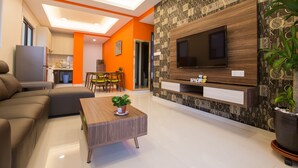 A modern living room with a sofa, a coffee table, a TV, and a kitchen in the background. - JAgape (Johor Bahru)