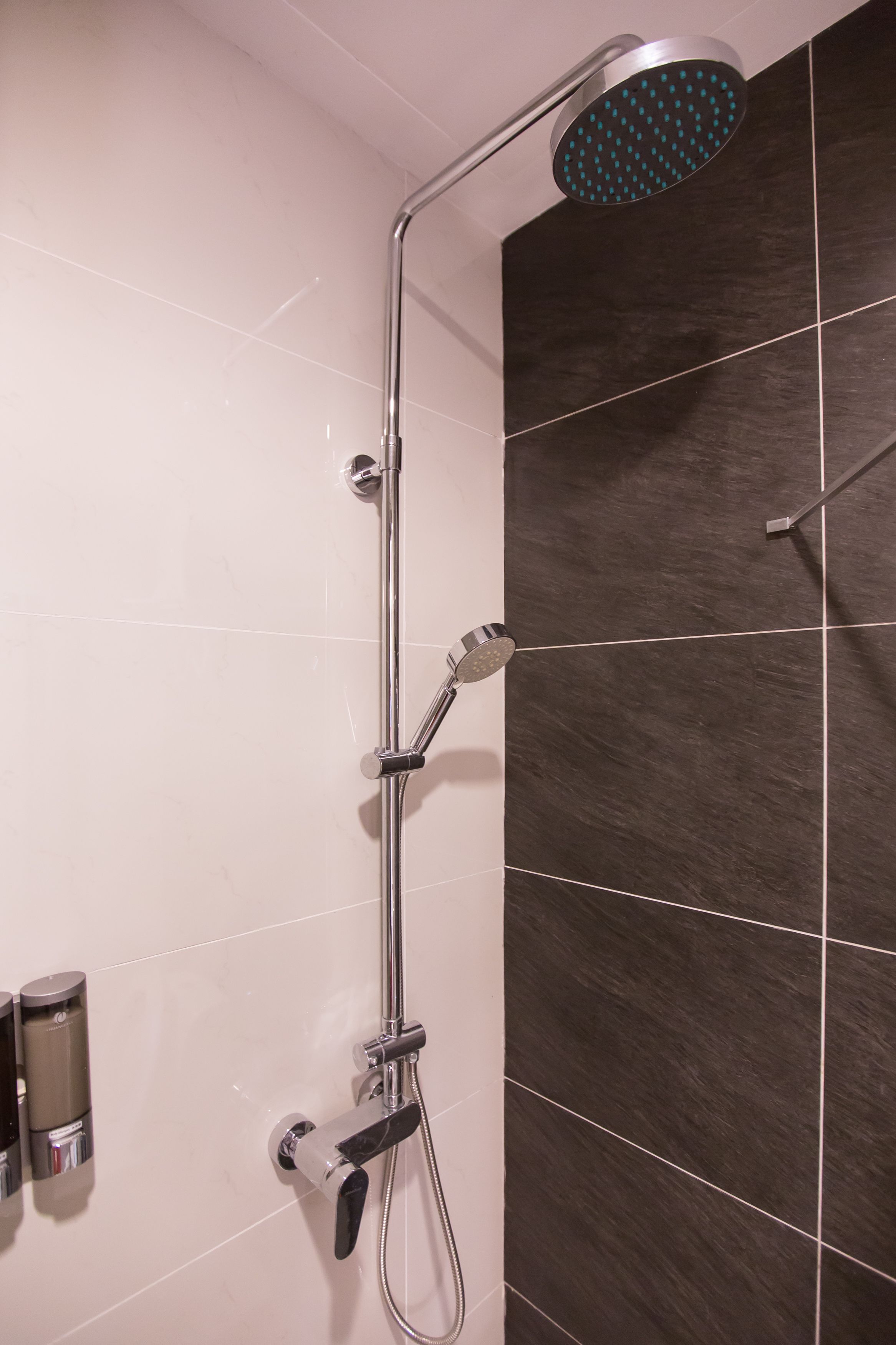 A modern shower with a handheld showerhead and a fixed rain showerhead mounted on a wall.