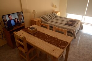 Une chambre à coucher avec un lit, une télévision, une table en bois et une chaise.