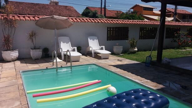 A swimming pool with lounge chairs and a sun umbrella. - Casa Sol de Maricá (Marica)