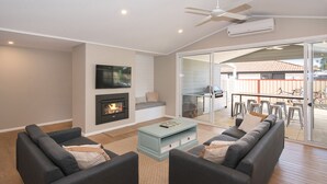 A modern living room with a fireplace, two sofas, a coffee table, and a TV. - SEA BREEZE - Beachside Family Haven (Broadwater)