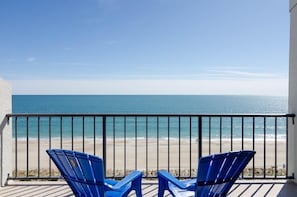 A balcony with two blue chairs overlooking a beach. - 2 Bedroom Oceanfront Condo in Station One! (Wrightsville Beach)