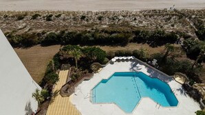 A hexagonal swimming pool with a view of the beach and ocean.