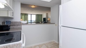 A modern kitchen with white cabinets, a built-in stove, and a refrigerator.