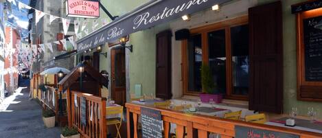 A restaurant with outdoor seating, a chalkboard menu, and a sign indicating it is a restaurant.