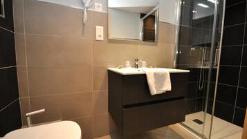 Un baño moderno con inodoro, lavamanos y zona de ducha.
