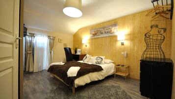 Een slaapkamer met een bed, een kapstok, een stoel, een lamp en een houten wand met een plank.