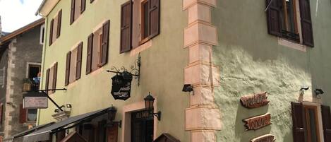 Un bâtiment doté de nombreuses fenêtres, d’un banc en bois à l’extérieur et d’une enseigne indiquant la présence d’un restaurant.