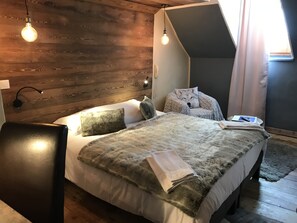 A modern bedroom with a wooden headboard, a large bed with a fluffy blanket, two bedside lamps, and a laptop on the nightstand. - Auberge de la paix (Briançon)