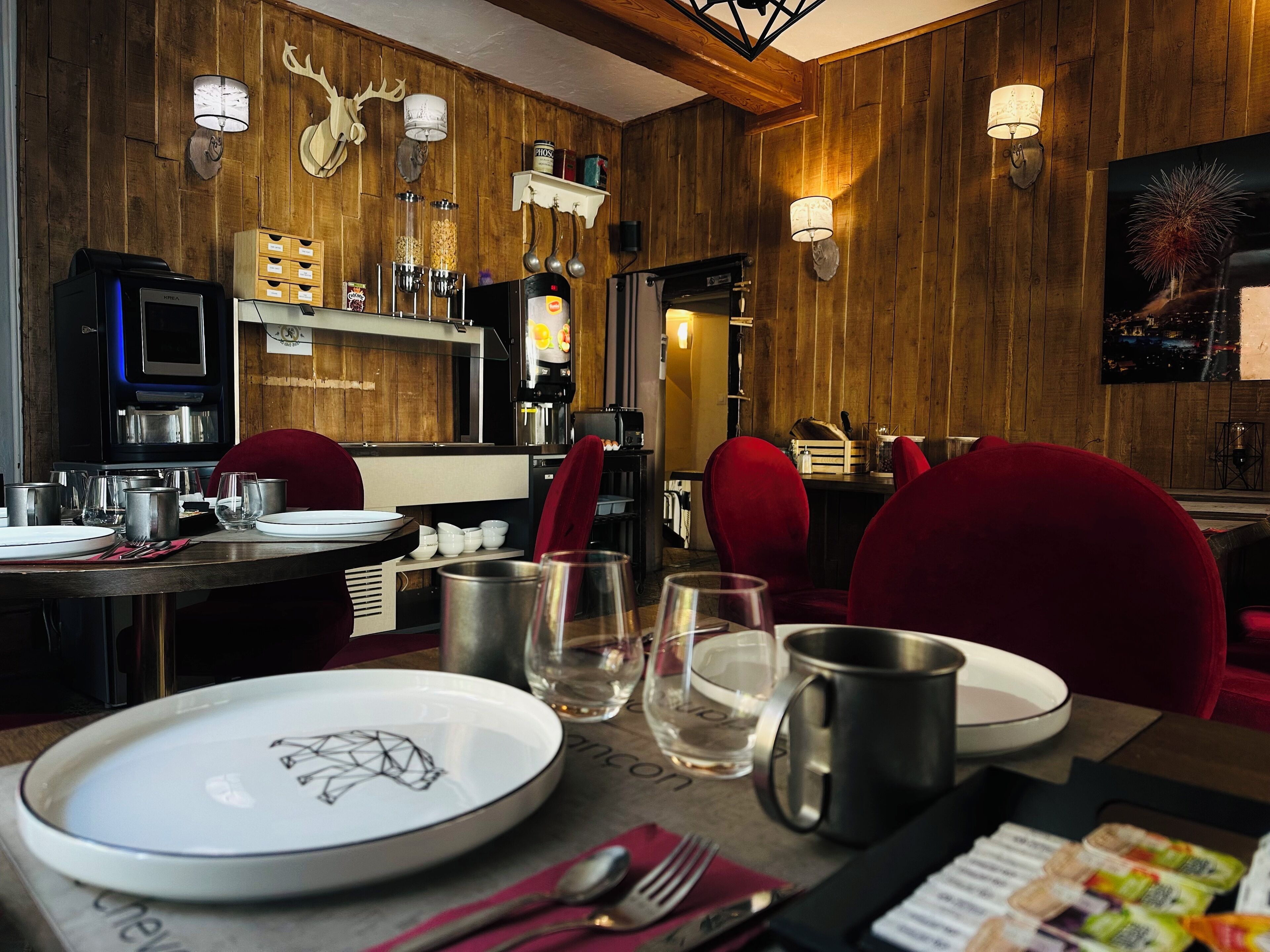 Een restaurant met houten wanden, rode bekleden stoelen en diverse serviesgoed op de tafels.