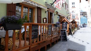 A restaurant with outdoor seating, wooden railings, and blackboards with menus. - Auberge de la paix (Briançon)