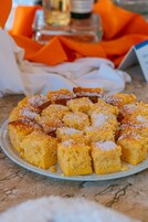 Un plato de cuadrados de pan de maíz espolvoreados con azúcar glas.