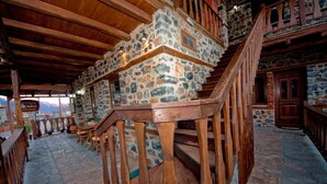 A rustic interior with stone walls, wooden beams, and a staircase. - Guesthouse Elati - Pella (Edessa)