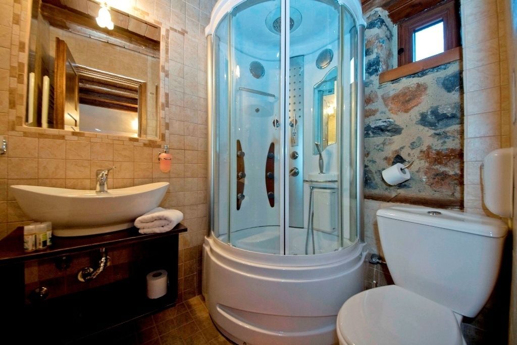 A bathroom with a glass-enclosed shower, a sink, and a toilet.