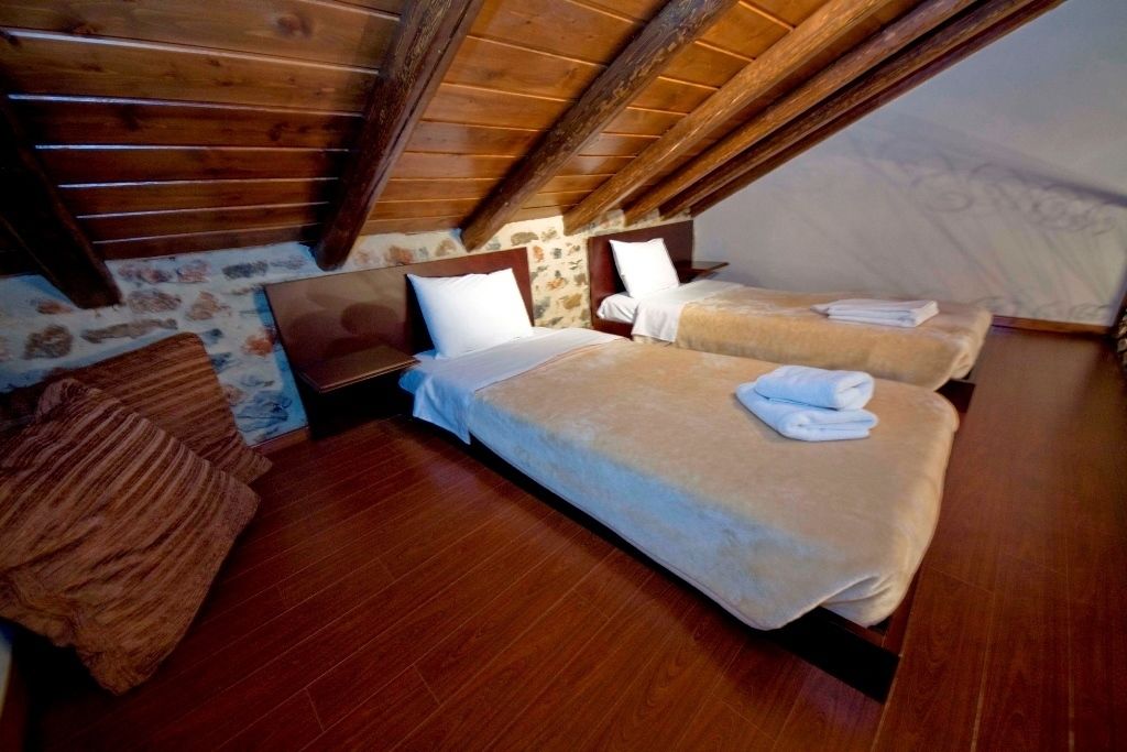 Un dormitorio acogedor en el ático con dos camas, vigas de madera y una pared de piedra.