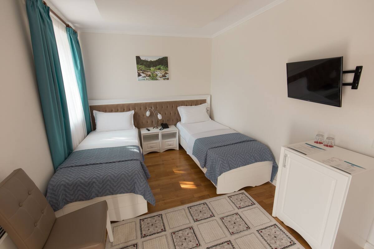 Une chambre d’hôtel avec deux lits, une télévision, un bureau et un petit placard.
