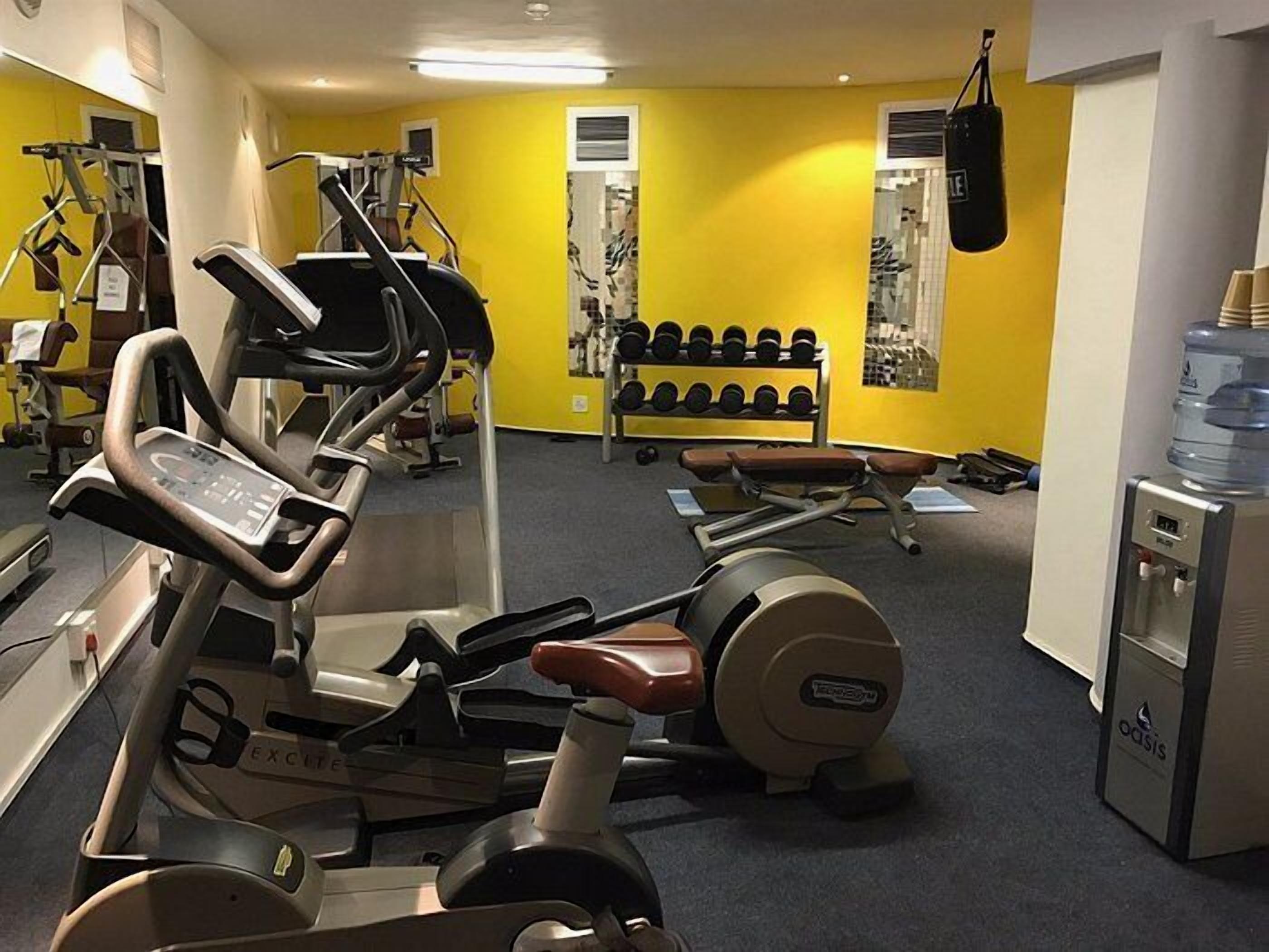 A gym with cardio equipment, dumbbells, and a punching bag.