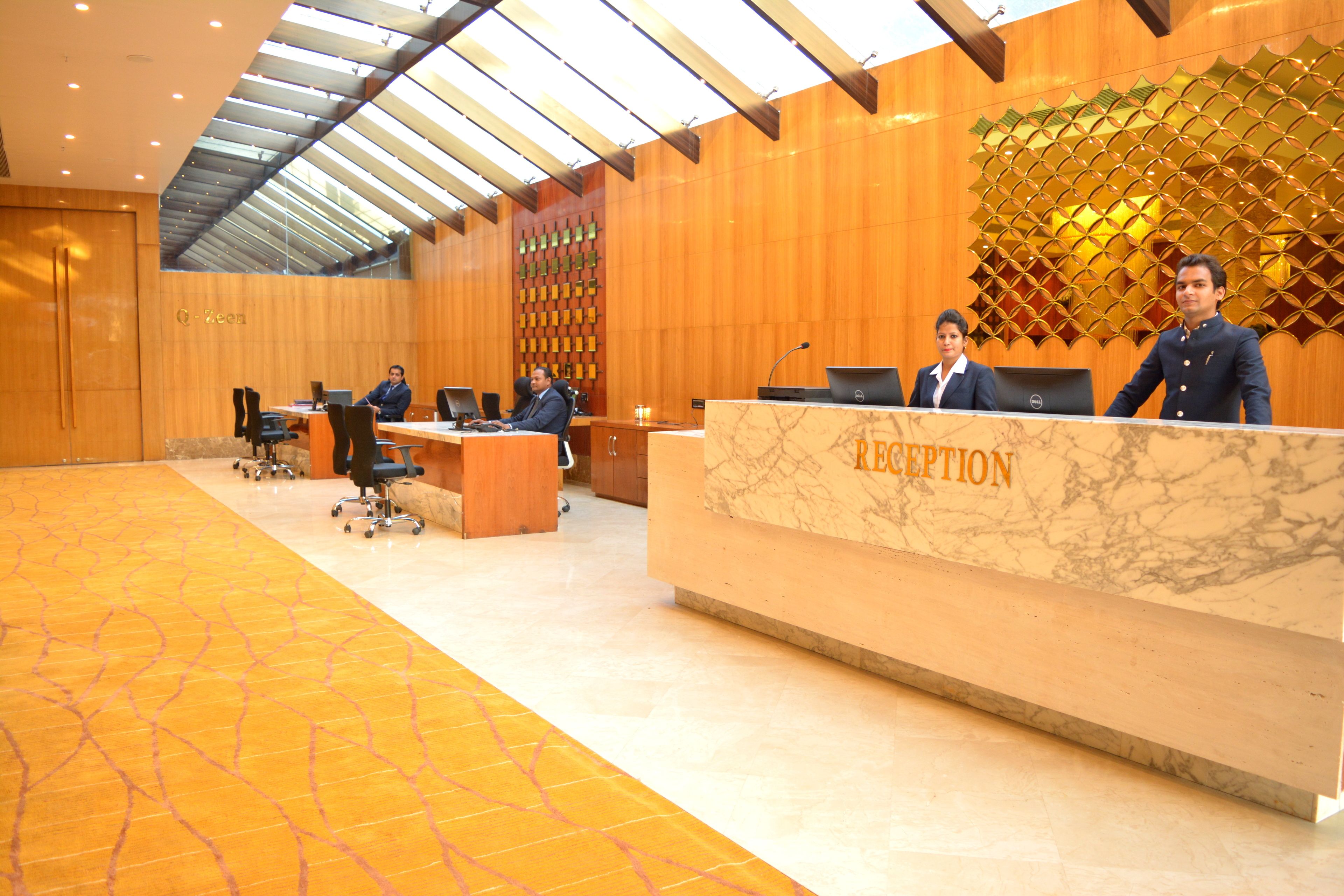 A reception area with a marble reception desk labeled "RECEPTION," multiple office chairs, and a high ceiling with a skylight.