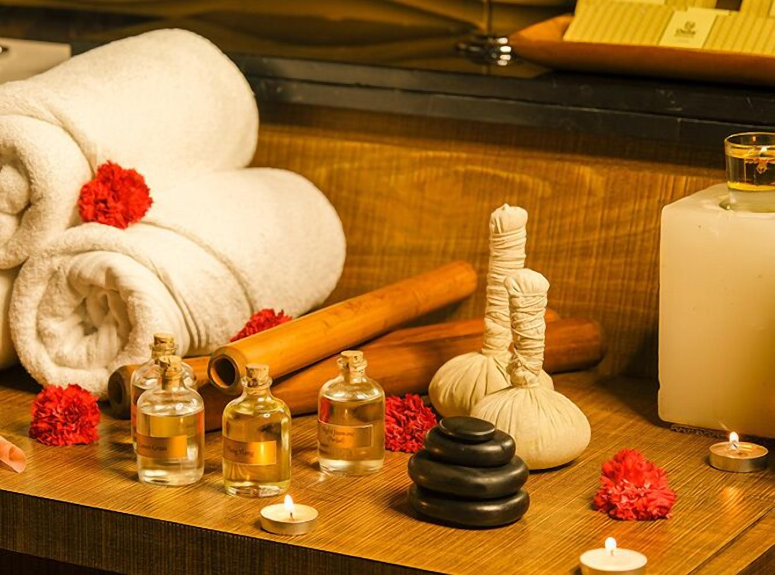 A spa setting with towels, candles, essential oils, and a massage stone.