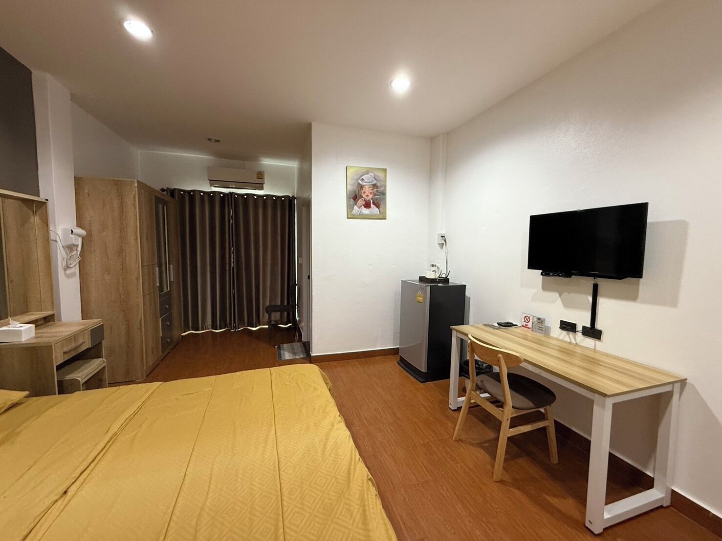 A hotel room with a bed, a desk, a chair, a TV, a wardrobe, and a curtain.