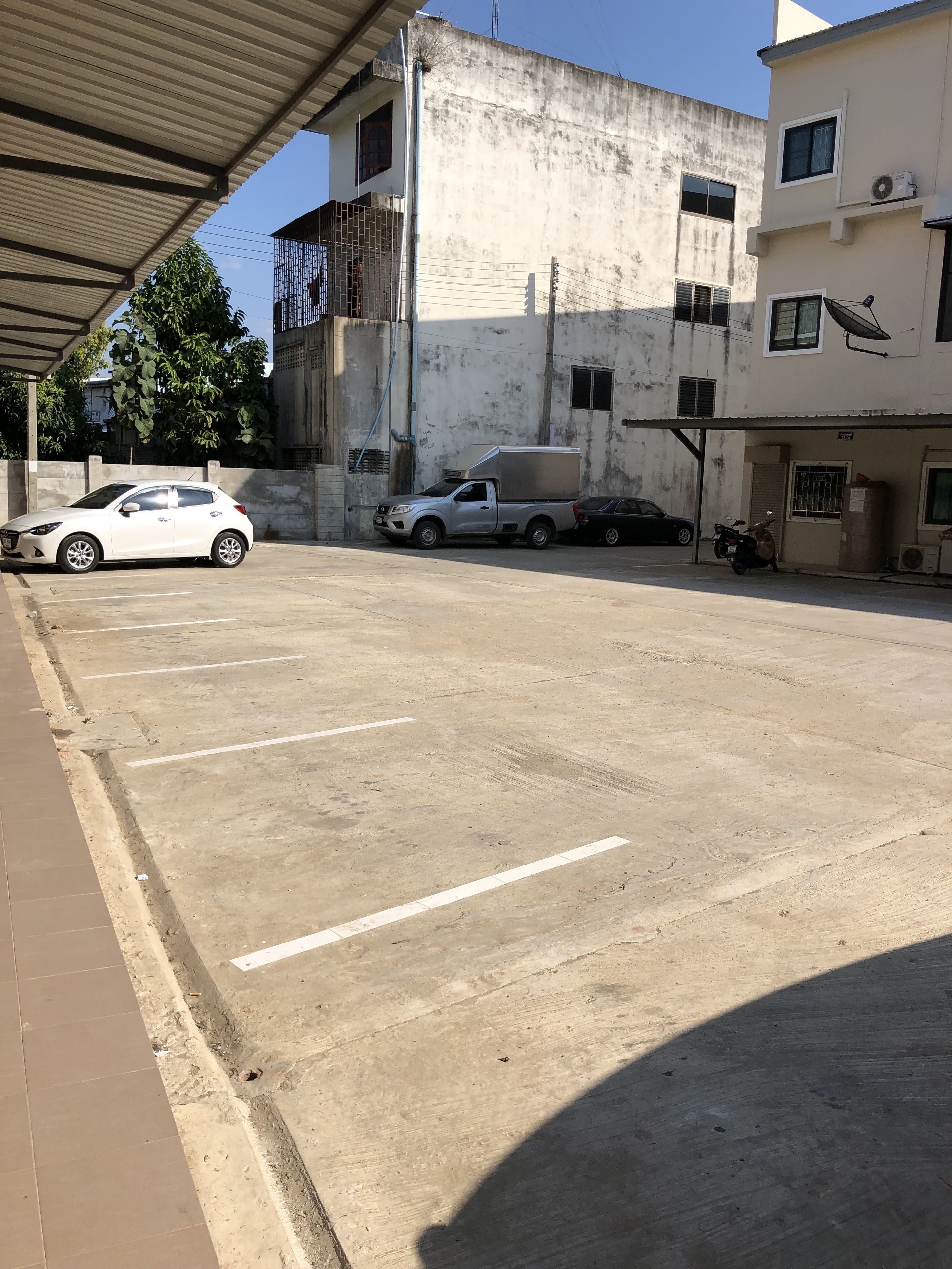 Un estacionamiento con un auto blanco y un camión de reparto.
