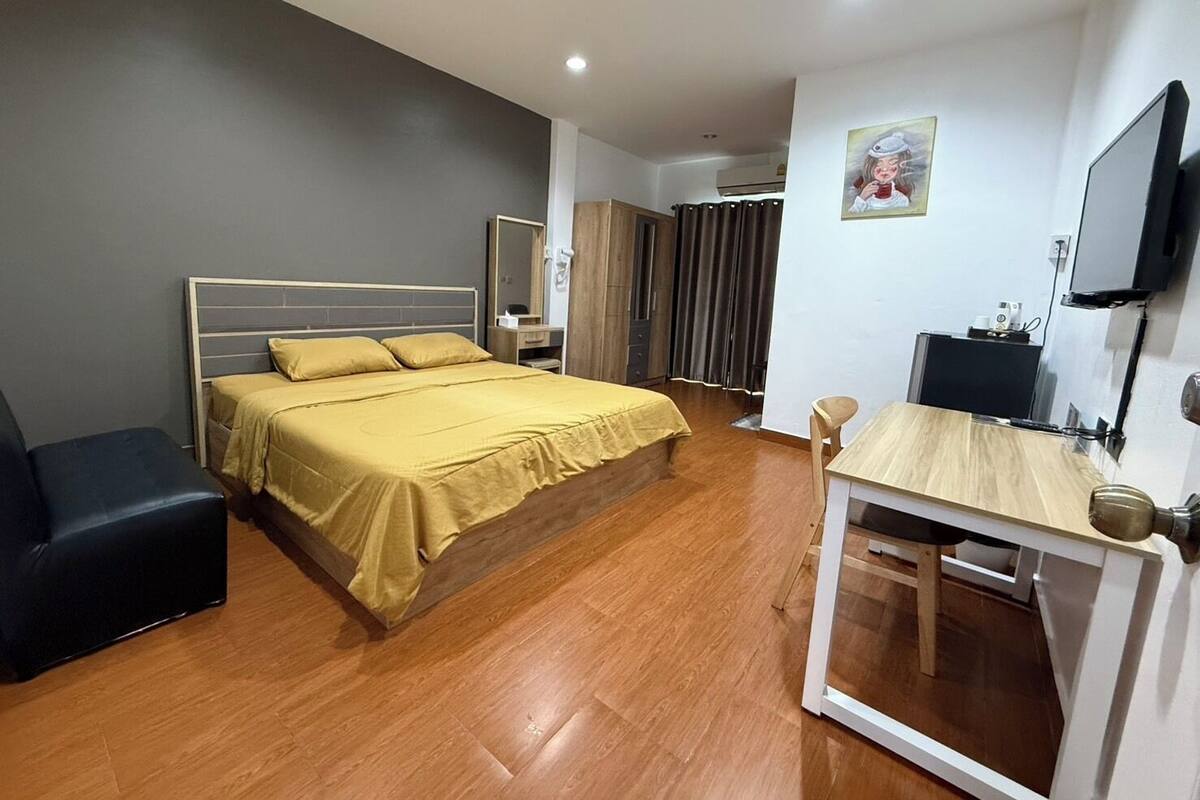 A bedroom with a bed, a desk, a chair, a TV, and a wardrobe.