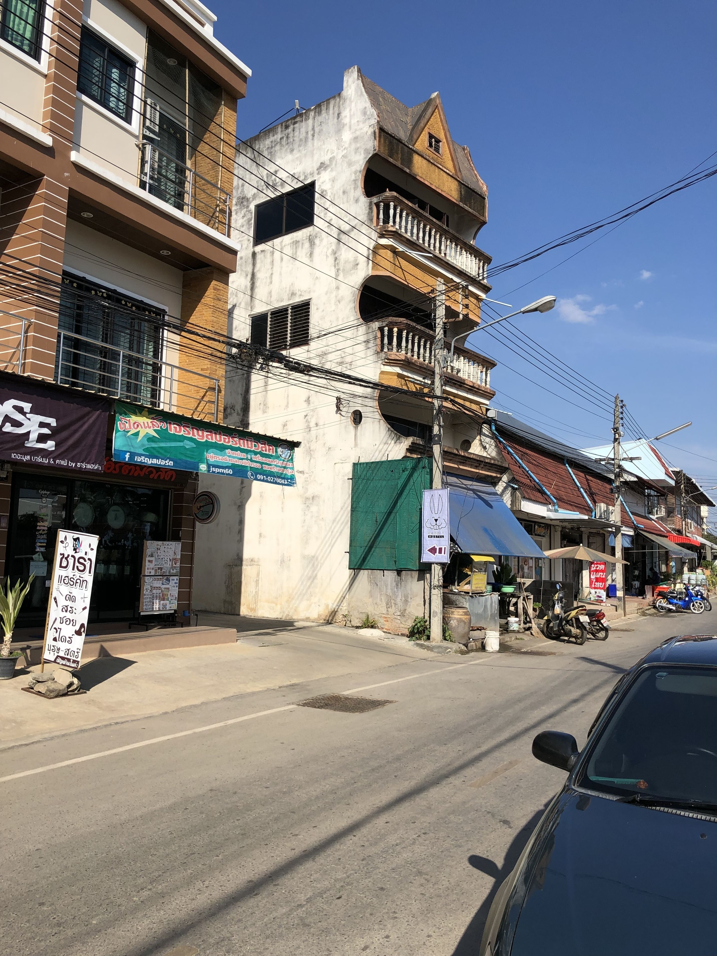 A street view with buildings, a signboard, and a parked car.