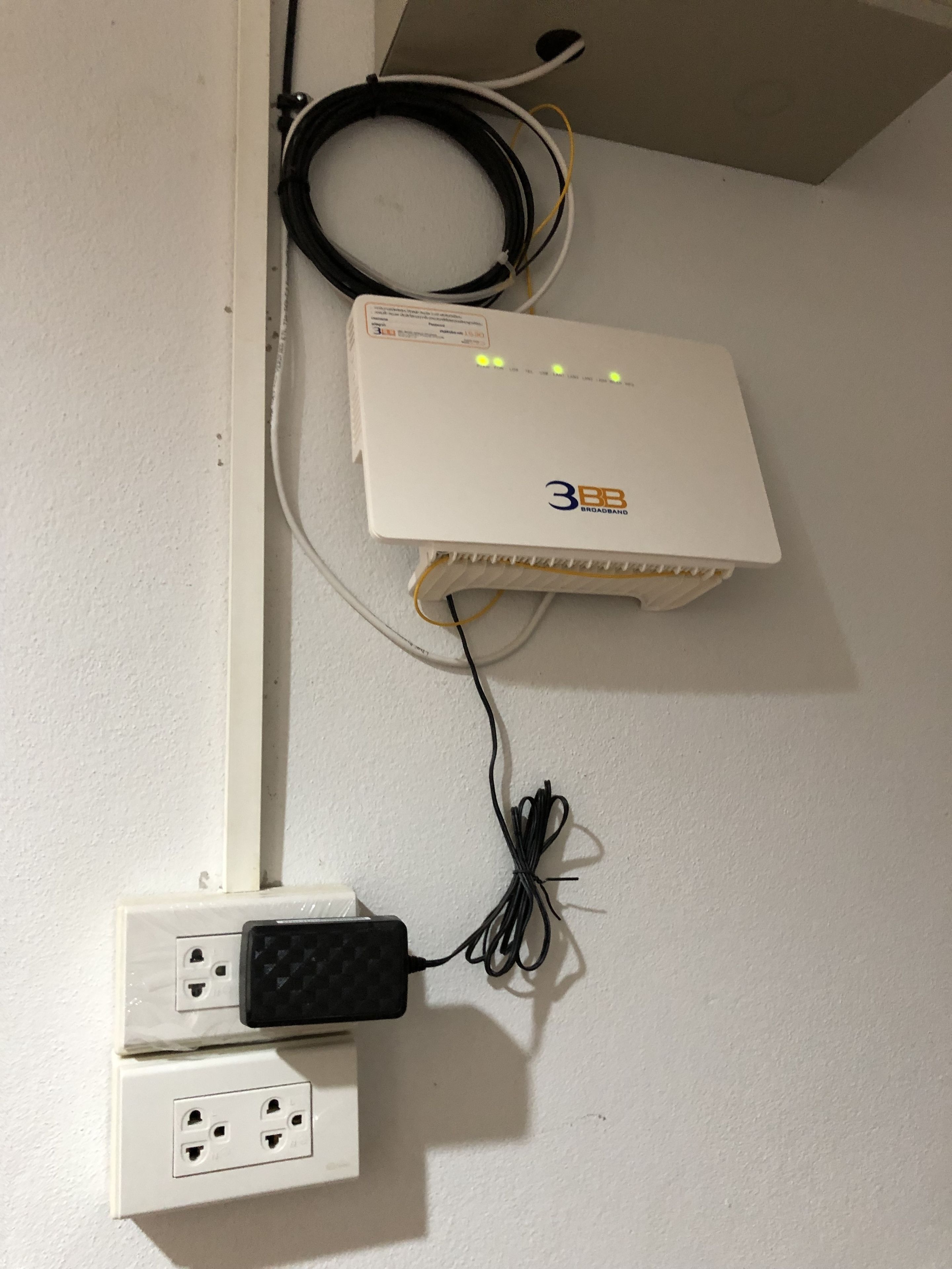 Un router de banda ancha 3BB montado en la pared con varios cables Ethernet conectados.