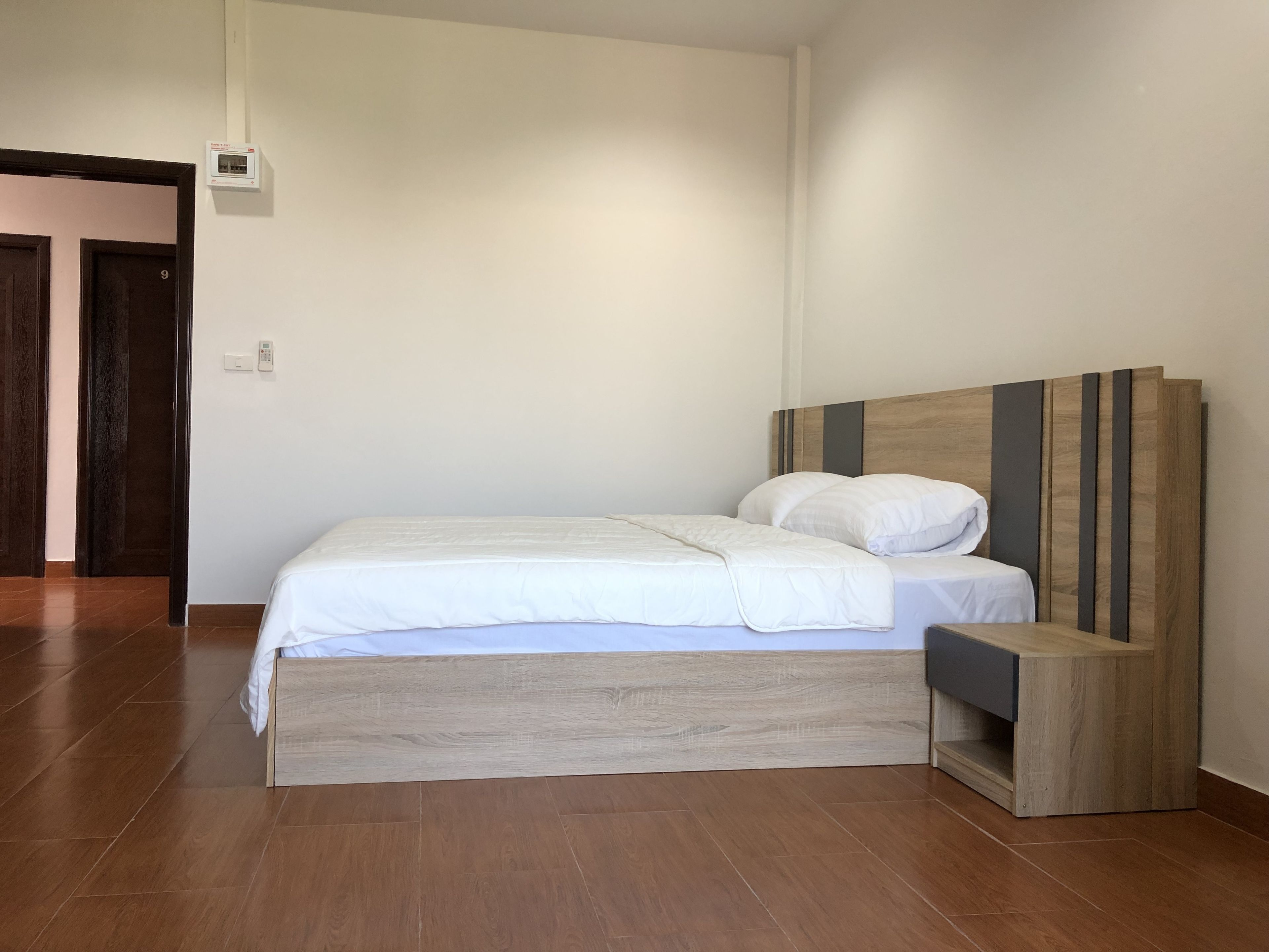 A modern bedroom with a wooden bed frame, white bedding, and a built-in nightstand.