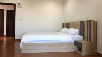 A modern bedroom with a wooden bed frame, white bedding, and a built-in nightstand.