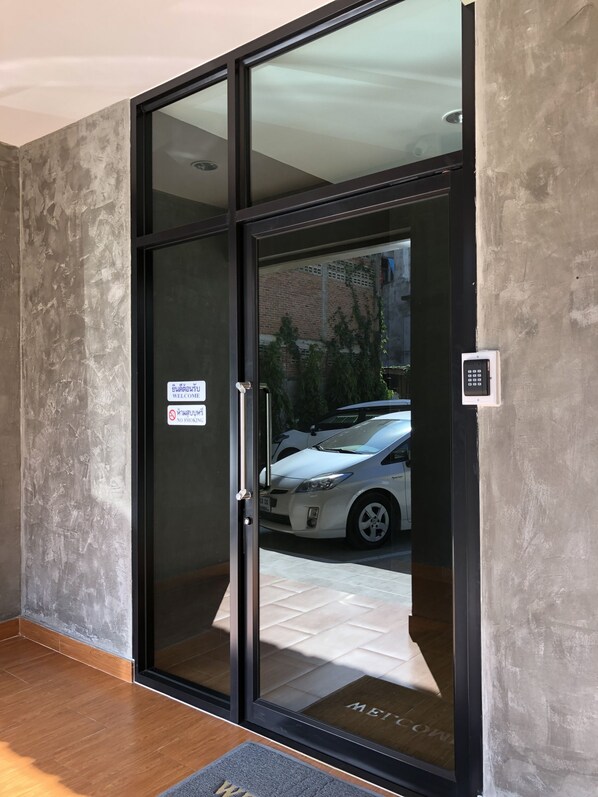 Entrada moderna de un edificio con puerta de vidrio, un cartel que dice