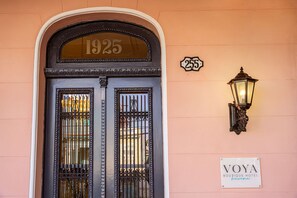 Step into the historic entrance of Voya Boutique Hotel, featuring a classic double door with a glass panel and a vintage lantern.
