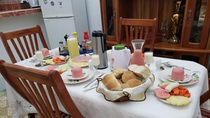 A dining table set with various food items and condiments, surrounded by wooden chairs. - Gaviota B&B (Havana)