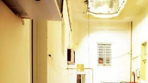 A narrow corridor with a white tiled floor, a door on the left, and a window with blinds on the right. - Gaviota B&B (Havana)