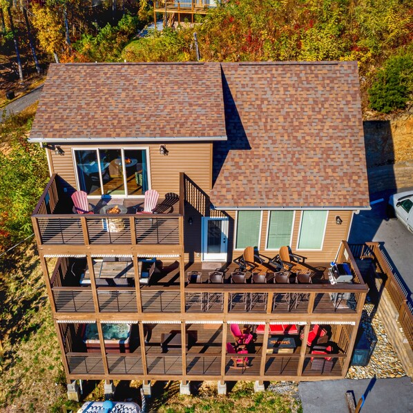 Una casa de dos pisos con terraza, ventanas amplias y mobiliario exterior.