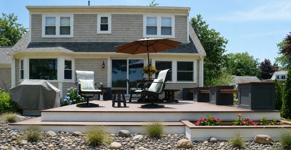 Una casa con un patio techado que cuenta con mobiliario exterior y una parrilla.
