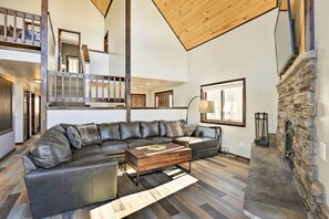 Amplia sala de estar con un sofá seccional en forma de L, una mesa de centro de madera y una chimenea de piedra.