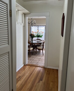Corredor que dá para uma sala de jantar com piso de madeira, uma mesa redonda e cadeiras.