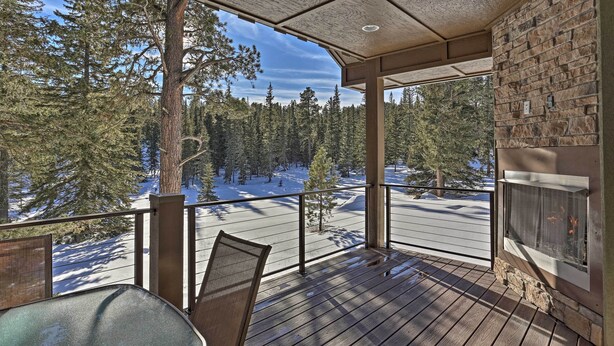 Eine Holzterrasse mit Kamin, mit Blick auf einen verschneiten Wald und eine Straße.