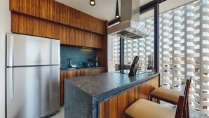 A modern kitchen with wooden cabinets, a stainless steel refrigerator, a granite countertop, and a window with a view of buildings. - Beautiful Condo in the heart of Zona Romantica! 2BD Condo for rent in Old Town, (Puerto Vallarta)