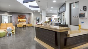 A modern reception area with a reception desk, seating area, and a large window providing natural light.