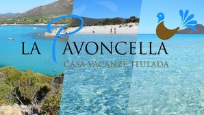 A coastal view with clear blue waters and a beach. Text indicates 'LA AVONCELLA' and 'CASA VACANZE TEULADA'. - Holiday home La Pavoncella app4 (Teulada)