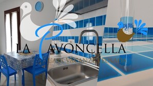 A modern kitchen with a sink, blue chairs, and a decorative bird on the wall. - Holiday home La Pavoncella app4 (Teulada)