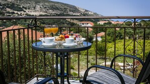 Varanda com mesa posta para café da manhã, com vista para uma paisagem montanhosa.