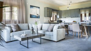 Uma sala de estar moderna com um sofá cinzento, uma mesa de centro e uma área de jantar com cadeiras de madeira.