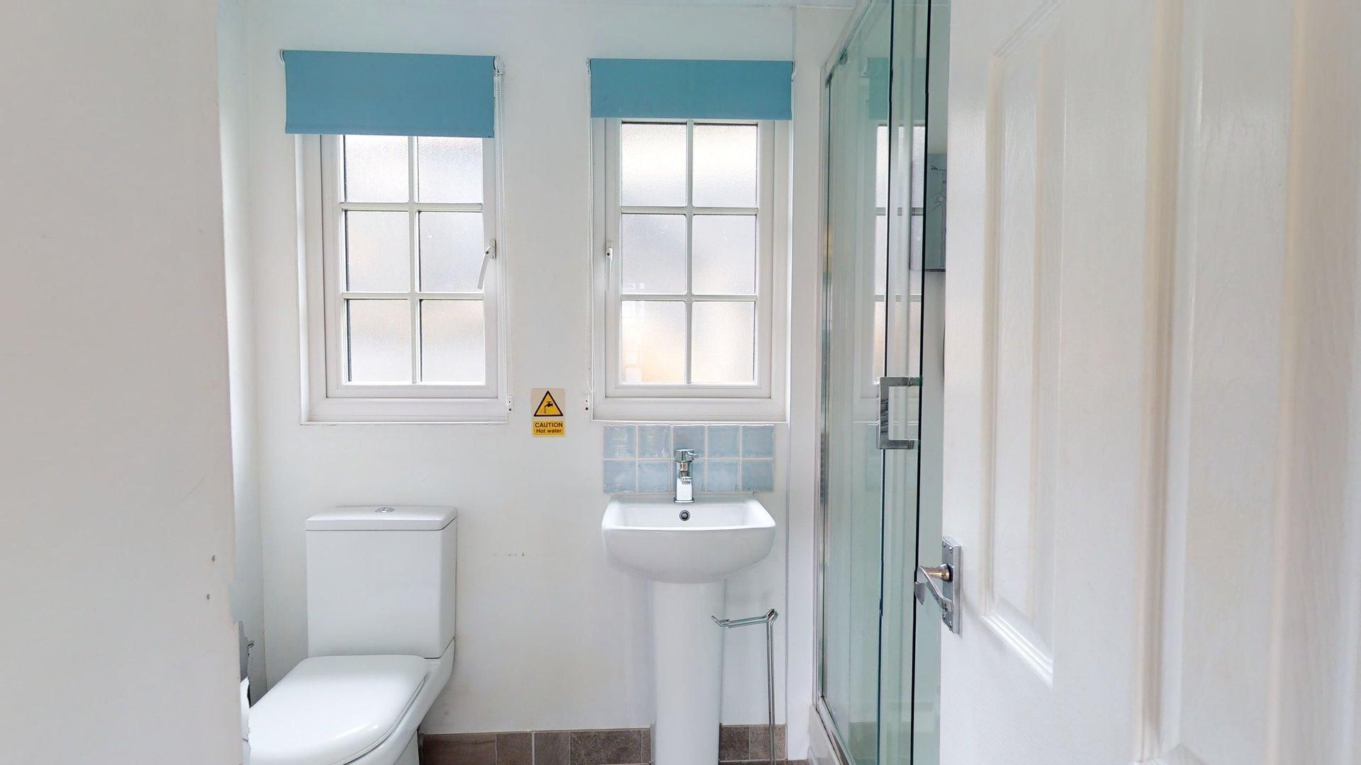 A bathroom with a toilet, sink, and shower area.