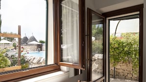 Ett rum med ett stort fönster med utsikt över en pool och ett utomhusområde med sittplatser.