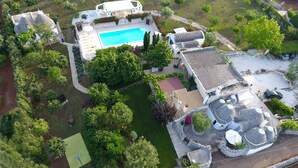 Ett flygbildsfoto av en fastighet med en swimmingpool, flera byggnader och omgivande grönska.
