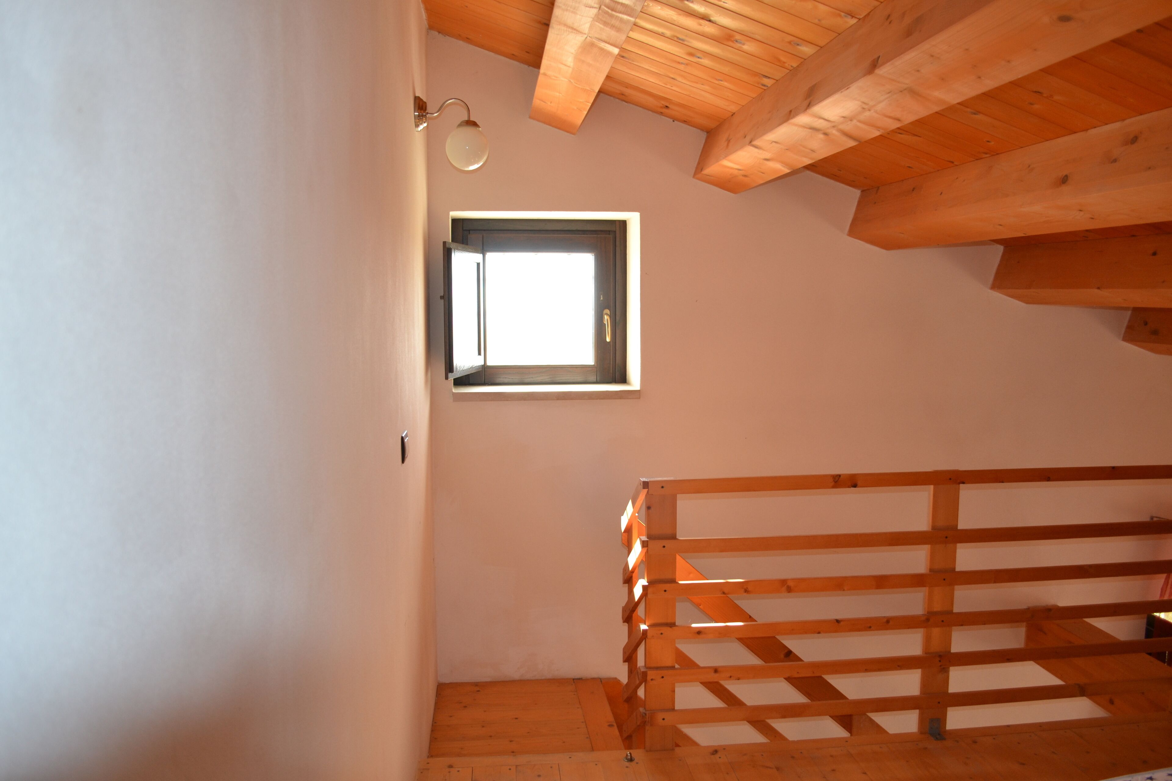 Une pièce avec un lit superposé en bois, une petite fenêtre et un plafond en pente.